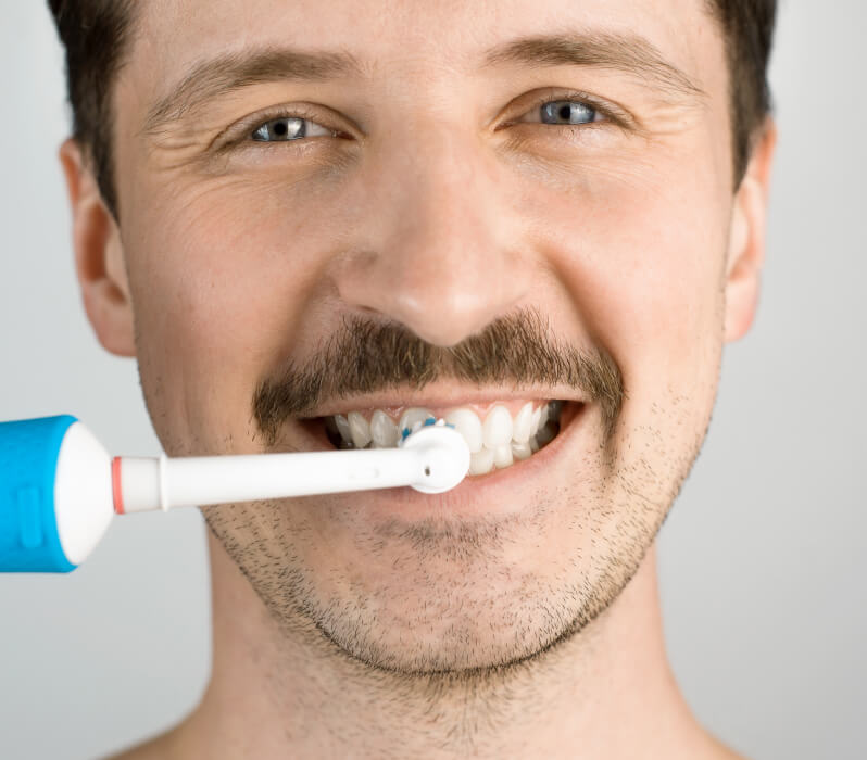 Man brushes teeth with an electric toothbrush
