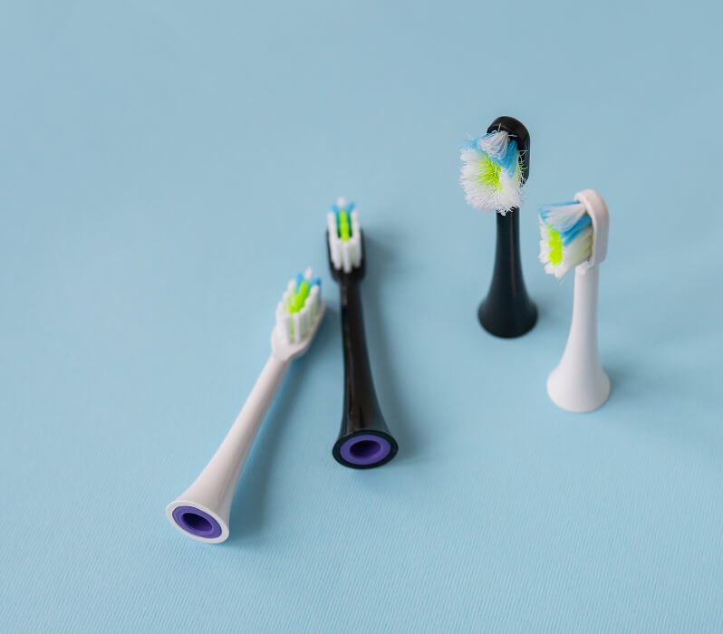 A used toothbrush head next to three brand new brush heads.
